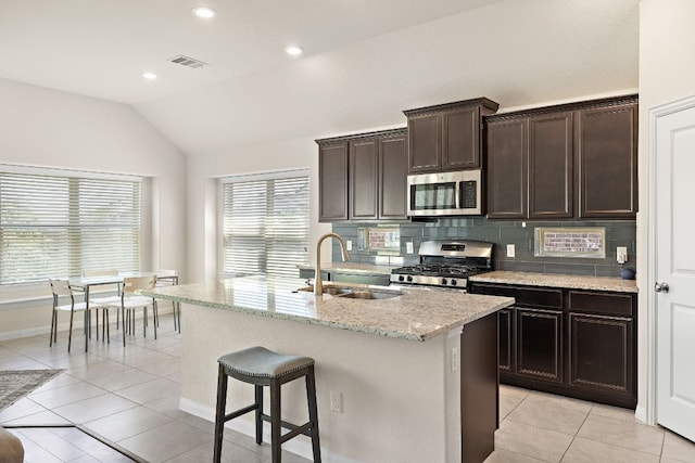 5012 Yucca Bloom Dr, Georgetown, TX 78626 - kitchen featuring stainless steel appliances, a sink, lofted ceiling, light tile patterned flooring, and light stone countertops