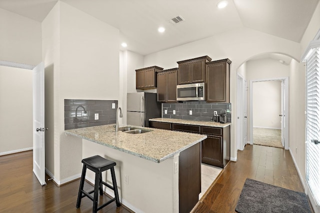 5012 Yucca Bloom Dr, Georgetown, TX 78626 - kitchen featuring stainless steel appliances, a sink, dark brown cabinetry, dark wood-type flooring, and arched walkways