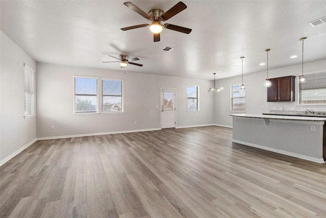 424 Wapiti Rd, Buda, TX 78610 - unfurnished living room featuring a ceiling fan, light wood-style flooring, baseboards, recessed lighting, and a chandelier