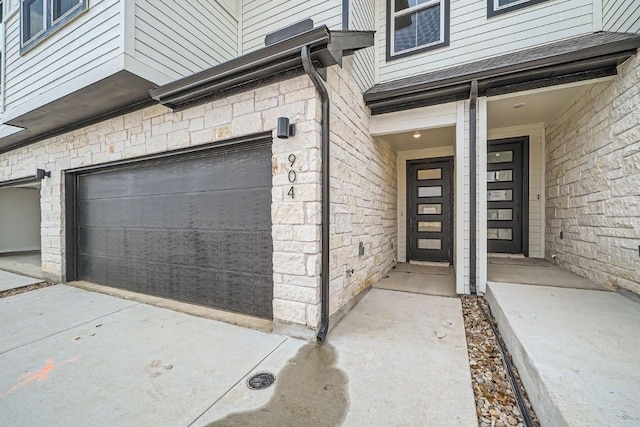 2600 Gattis School Rd Unit 1102, Round Rock, TX 78664 - doorway to property with a garage, stone siding, and concrete driveway