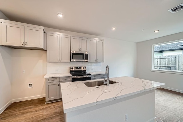 2600 Gattis School Rd Unit 1102, Round Rock, TX 78664 - kitchen with stainless steel appliances, a sink, wood finished floors, light stone countertops, and tasteful backsplash
