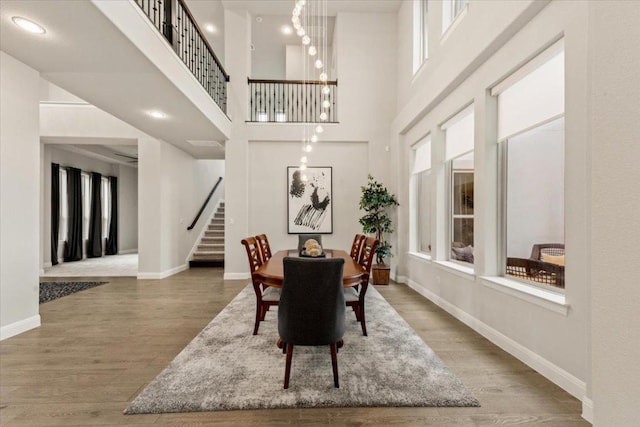 2037 Portobello Rd, Leander, TX 78641 - dining room with stairs, wood finished floors, a high ceiling, and a chandelier