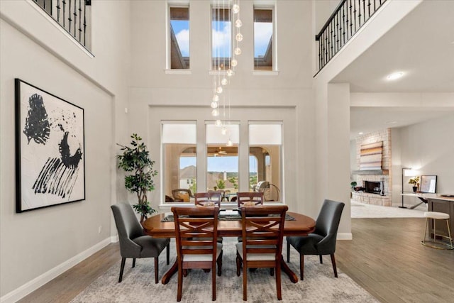 2037 Portobello Rd, Leander, TX 78641 - dining space featuring a large fireplace, a towering ceiling, and wood finished floors