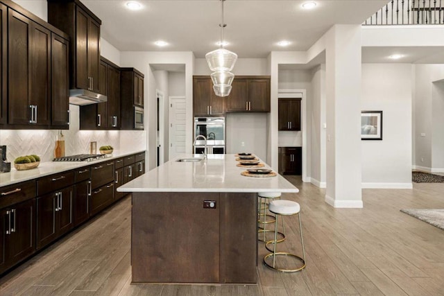 2037 Portobello Rd, Leander, TX 78641 - kitchen with a sink, baseboards, under cabinet range hood, decorative backsplash, and appliances with stainless steel finishes