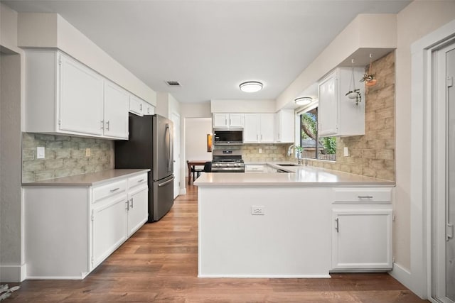 12025 Cherie Dr, Austin, TX 78758 - kitchen with stainless steel appliances, a sink, a peninsula, white cabinets, and backsplash