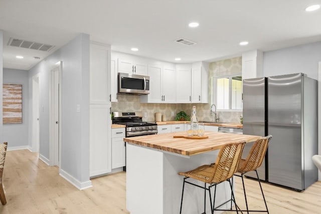4802 Brighton Rd, Austin, TX 78745 - kitchen with appliances with stainless steel finishes, butcher block countertops, light wood-style flooring, white cabinets, and recessed lighting