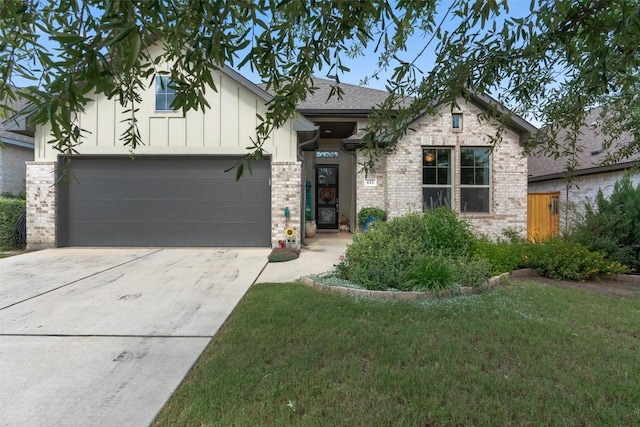 653 Coyote Creek Way, Kyle, TX 78640 - view of front facade featuring a garage, concrete driveway, a front lawn, brick siding, and a shingled roof