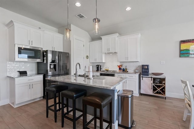 653 Coyote Creek Way, Kyle, TX 78640 - kitchen with stainless steel appliances, a sink, light wood-style floors, tasteful backsplash, and recessed lighting