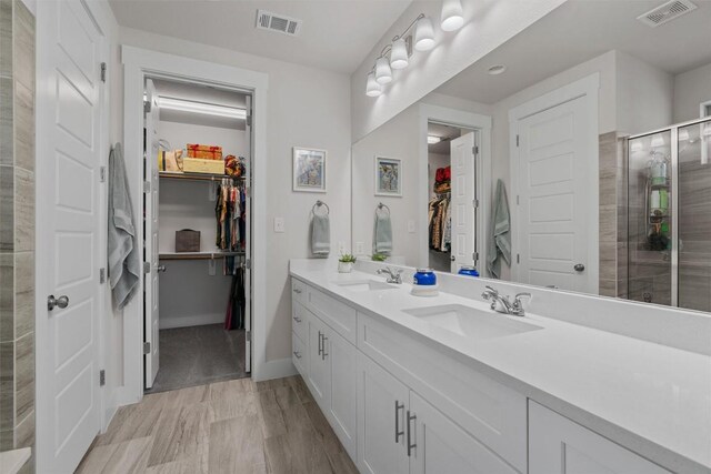 653 Coyote Creek Way, Kyle, TX 78640 - full bathroom featuring a walk in closet, double vanity, a shower stall, and baseboards