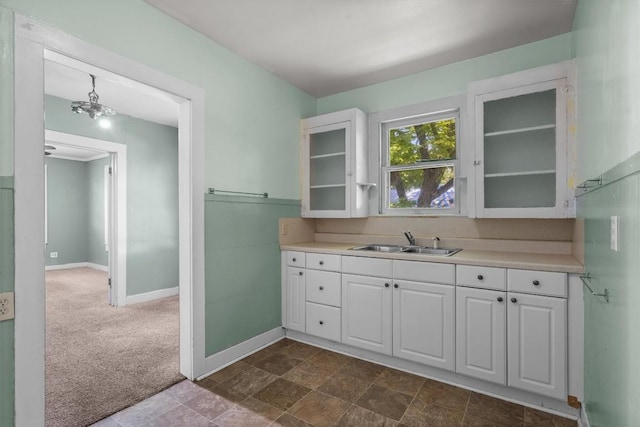 604 Harris Ave, Austin, TX 78705 - kitchen featuring a sink, white cabinets, light countertops, glass insert cabinets, and baseboards