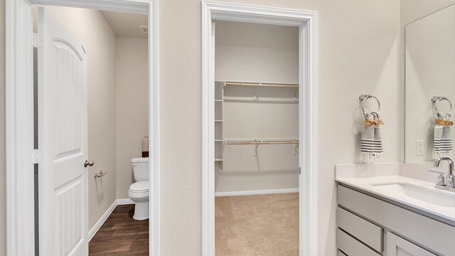166 Caddo Bnd, Kyle, TX 78640 - bathroom featuring toilet, vanity, a spacious closet, and wood finished floors