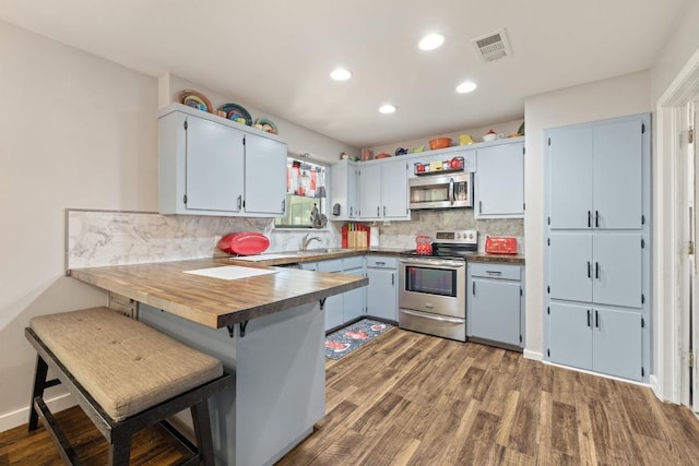 3704 Del Rio Ct, Georgetown, TX 78628 - kitchen with stainless steel appliances, a peninsula, backsplash, wood finished floors, and recessed lighting