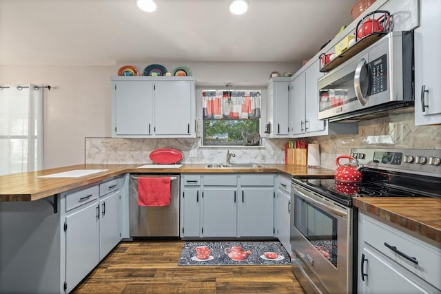 3704 Del Rio Ct, Georgetown, TX 78628 - kitchen with stainless steel appliances, a peninsula, dark wood-type flooring, backsplash, and wood counters