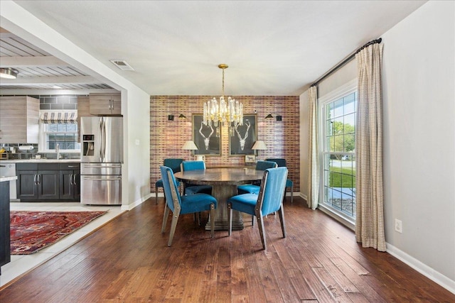 5808 Marilyn Dr, Austin, TX 78757 - dining space featuring hardwood / wood-style flooring, a chandelier, baseboards, and brick wall