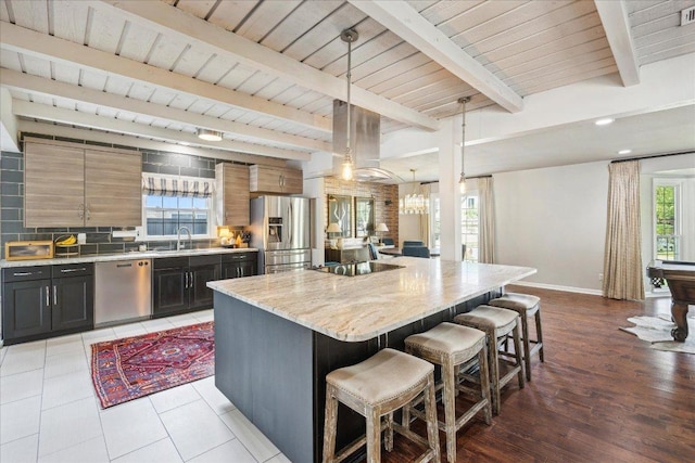 5808 Marilyn Dr, Austin, TX 78757 - kitchen featuring appliances with stainless steel finishes, a breakfast bar area, tasteful backsplash, a center island, and baseboards