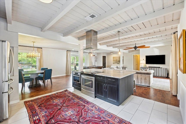 5808 Marilyn Dr, Austin, TX 78757 - kitchen featuring stainless steel appliances, island exhaust hood, dark cabinets, open floor plan, and light stone counters