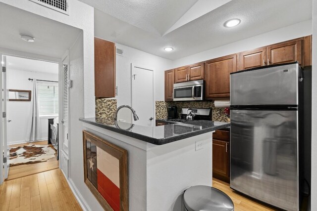 3601 Menchaca Rd Unit 215, Austin, TX 78704 - kitchen with appliances with stainless steel finishes, backsplash, light wood-style flooring, a sink, and vaulted ceiling