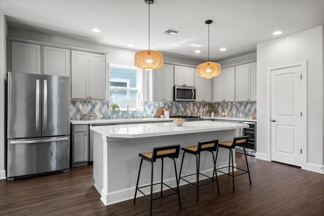 8103 Chrysler Bnd, Austin, TX 78744 - kitchen with appliances with stainless steel finishes, wine cooler, dark wood-type flooring, a breakfast bar, and tasteful backsplash