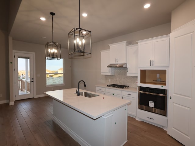 1200 Snowdrop Dr, Georgetown, TX 78628 - kitchen featuring oven, backsplash, a kitchen island with sink, dark wood finished floors, and light countertops