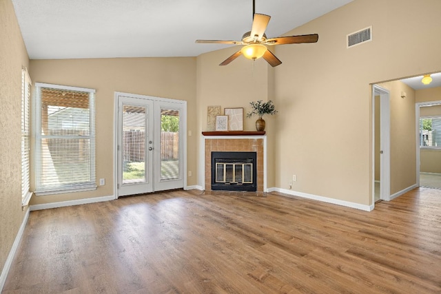 11611 Prairie Hen Ln, Austin, TX 78758 - unfurnished living room with high vaulted ceiling, wood finished floors, ceiling fan, a tiled fireplace, and baseboards
