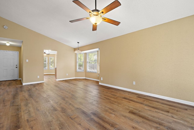 11611 Prairie Hen Ln, Austin, TX 78758 - spare room featuring a ceiling fan, vaulted ceiling, dark wood-style floors, baseboards, and a chandelier