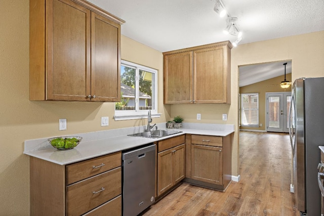 11611 Prairie Hen Ln, Austin, TX 78758 - kitchen featuring stainless steel appliances, a sink, light wood-type flooring, light countertops, and vaulted ceiling