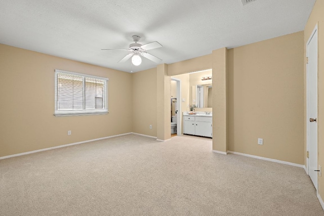 11611 Prairie Hen Ln, Austin, TX 78758 - unfurnished bedroom featuring light carpet, baseboards, ensuite bath, a textured ceiling, and a ceiling fan