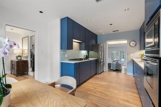 2103 W 10th St, Austin, TX 78703 - kitchen with stainless steel appliances, light countertops, tasteful backsplash, light wood-style flooring, and blue cabinets