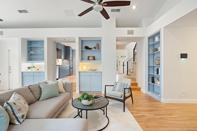 2103 W 10th St, Austin, TX 78703 - living room with built in shelves, ceiling fan, baseboards, light wood-style floors, and stairway