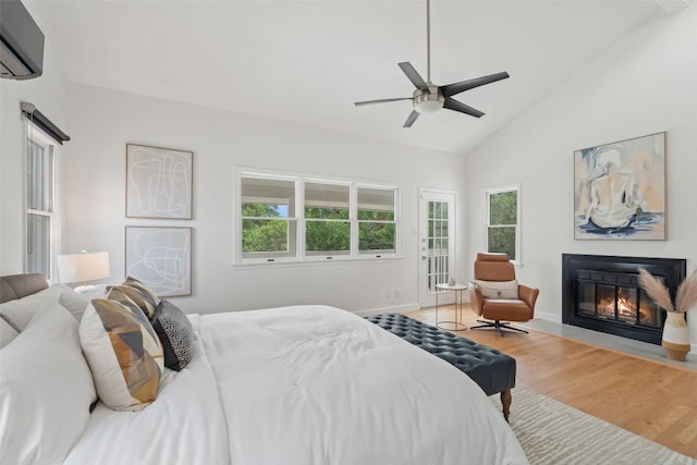 2103 W 10th St, Austin, TX 78703 - bedroom featuring a wall unit AC, multiple windows, a fireplace with flush hearth, wood finished floors, and high vaulted ceiling