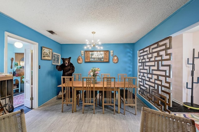 3304 Whitepine Dr, Austin, TX 78757 - dining space featuring a chandelier, wood finished floors, and a textured ceiling