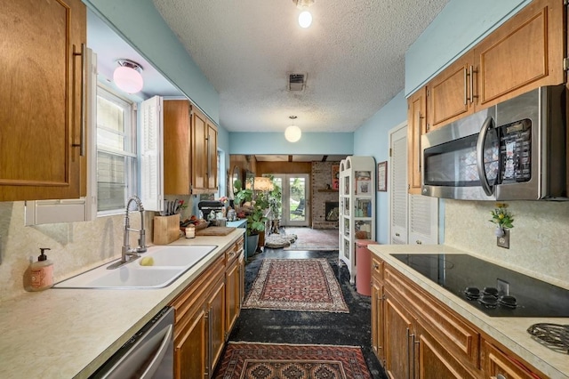 3304 Whitepine Dr, Austin, TX 78757 - kitchen featuring appliances with stainless steel finishes, a textured ceiling, brown cabinets, and light countertops
