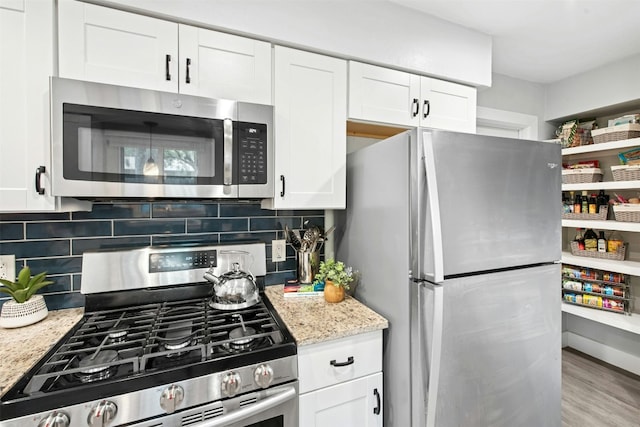 1804 Matthews Ln Unit B, Austin, TX 78745 - kitchen with stainless steel appliances, backsplash, white cabinetry, and light stone counters