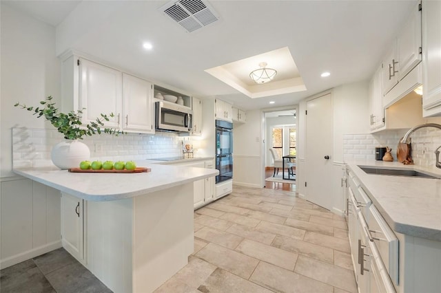 9803 Talleyran Dr, Austin, TX 78750 - kitchen featuring a sink, black appliances, decorative backsplash, a peninsula, and white cabinetry
