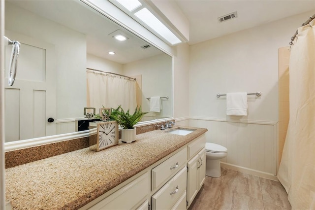 9803 Talleyran Dr, Austin, TX 78750 - full bath featuring toilet, vanity, a wainscoted wall, curtained shower, and recessed lighting