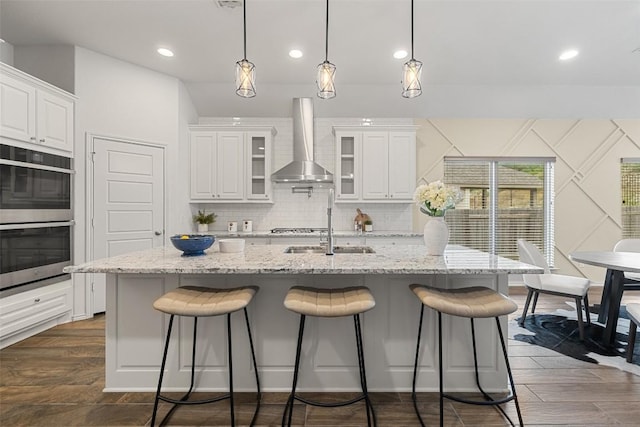 400 Saturnia Dr, Georgetown, TX 78613 - kitchen with stainless steel double oven, wall chimney exhaust hood, white cabinetry, and recessed lighting