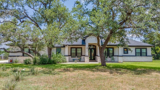 410 Woodland Oaks Trl, Buda, TX 78610 - view of front of house featuring french doors, a front yard, stucco siding, stone siding, and roof with shingles