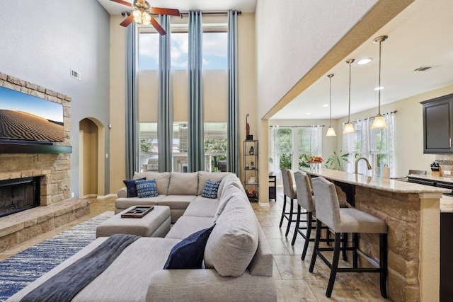 1312 Ravensbrook Bnd, Cedar Park, TX 78613 - living area featuring a high ceiling, a fireplace, a ceiling fan, arched walkways, and baseboards