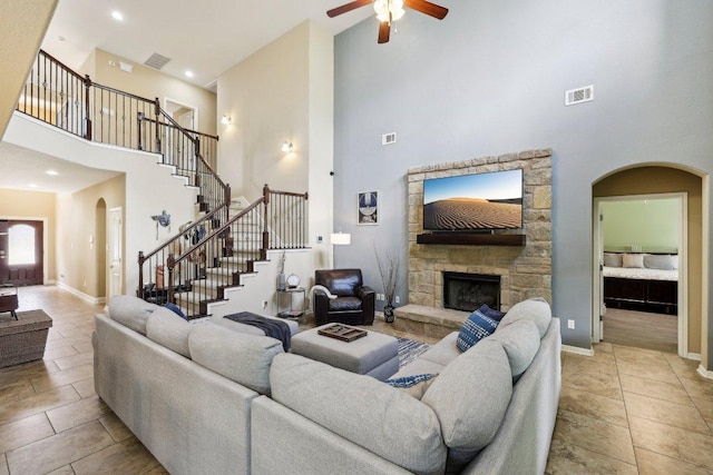 1312 Ravensbrook Bnd, Cedar Park, TX 78613 - living area with a towering ceiling, arched walkways, ceiling fan, stairs, and a stone fireplace