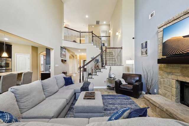 1312 Ravensbrook Bnd, Cedar Park, TX 78613 - living area with arched walkways, a high ceiling, stairway, a fireplace, and baseboards