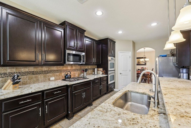 1312 Ravensbrook Bnd, Cedar Park, TX 78613 - kitchen featuring a sink, appliances with stainless steel finishes, arched walkways, decorative backsplash, and decorative light fixtures