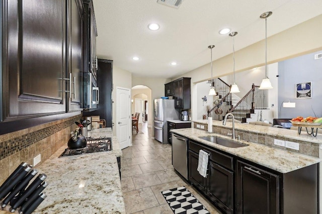 1312 Ravensbrook Bnd, Cedar Park, TX 78613 - kitchen featuring a sink, stainless steel appliances, arched walkways, decorative backsplash, and light stone countertops