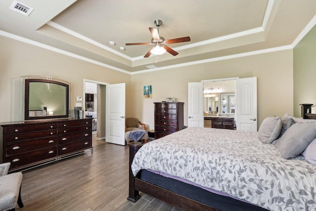 1312 Ravensbrook Bnd, Cedar Park, TX 78613 - bedroom featuring a tray ceiling, dark wood finished floors, crown molding, ensuite bathroom, and ceiling fan