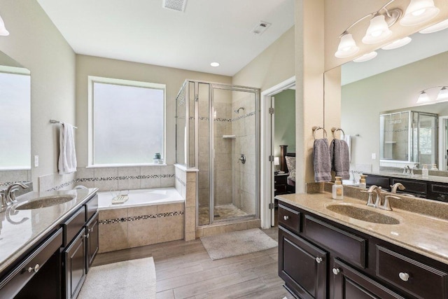1312 Ravensbrook Bnd, Cedar Park, TX 78613 - bathroom with two vanities, a stall shower, a bath, and wood finished floors