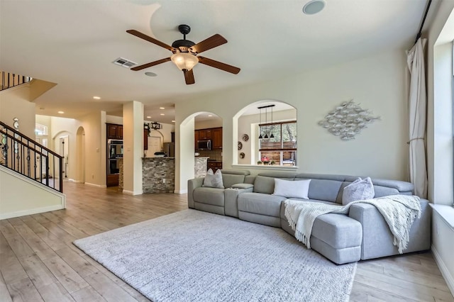 2835 Checker Dr, Cedar Park, TX 78613 - living area featuring ceiling fan, light wood-style floors, arched walkways, and stairs