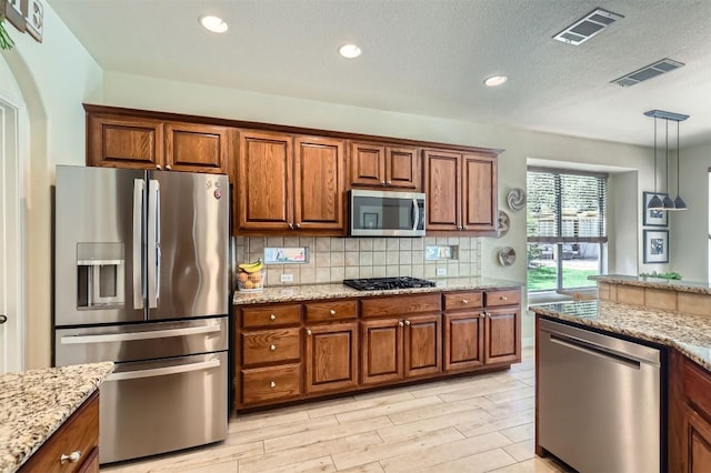 2835 Checker Dr, Cedar Park, TX 78613 - kitchen with stainless steel appliances, brown cabinetry, decorative light fixtures, recessed lighting, and a textured ceiling