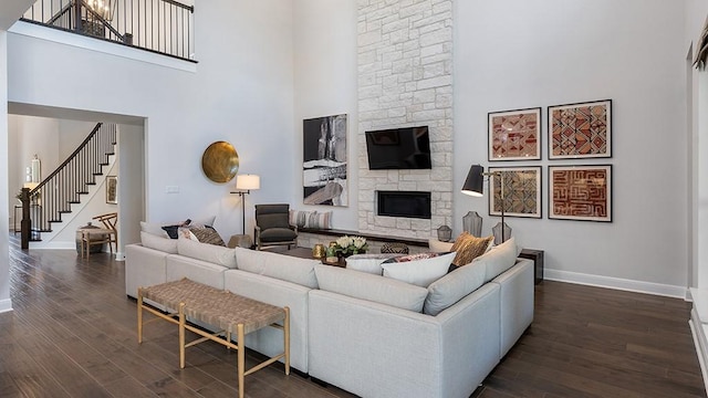 1912 Asti Ln, Leander, TX 78641 - living room featuring a high ceiling, stairs, dark wood finished floors, and a stone fireplace