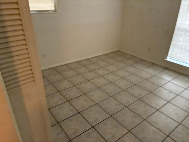 620 Amesbury Ln, Austin, TX 78752 - empty room with light tile patterned floors, plenty of natural light, and baseboards