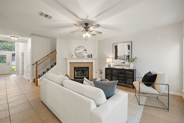 4535 Wandering Vine Trl, Round Rock, TX 78665 - living area with light tile patterned floors, a ceiling fan, a tile fireplace, stairs, and baseboards
