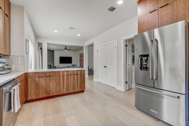 10840 Redmond Rd, Austin, TX 78739 - kitchen featuring appliances with stainless steel finishes, light wood-type flooring, light countertops, brown cabinetry, and open floor plan